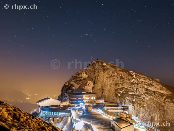 The illuminated summit of Mount Pilatus at night under a starry sky