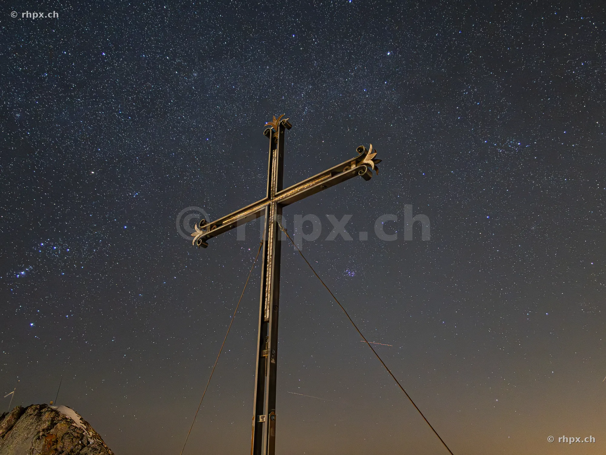 The summit cross on Mount Pilatus against a clear starry night sky