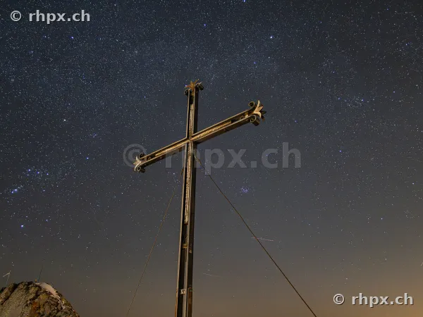 The summit cross on Mount Pilatus against a clear starry night sky