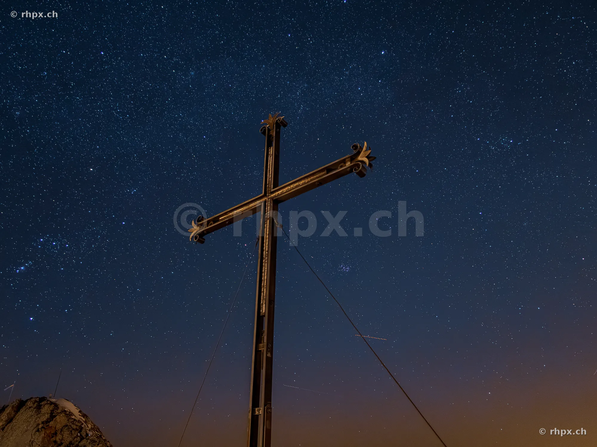 Summit cross on Mount Pilatus with a starry sky in the background