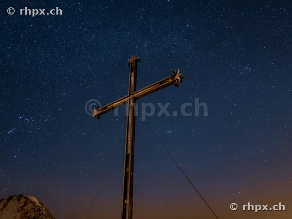 Summit cross on Mount Pilatus with a starry sky in the background