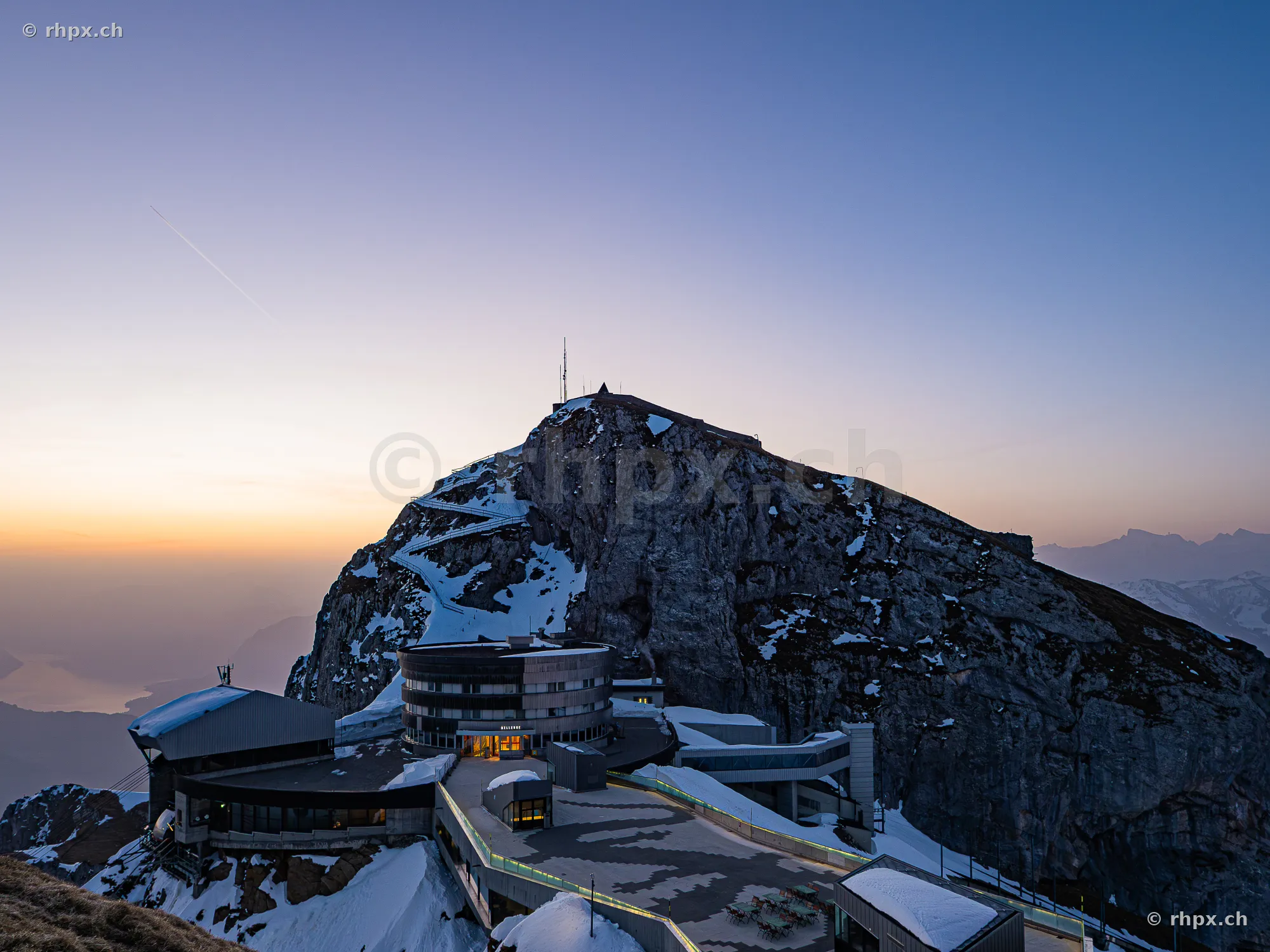 View of the Pilatus Kulm hotel on the snowy summit during twilight