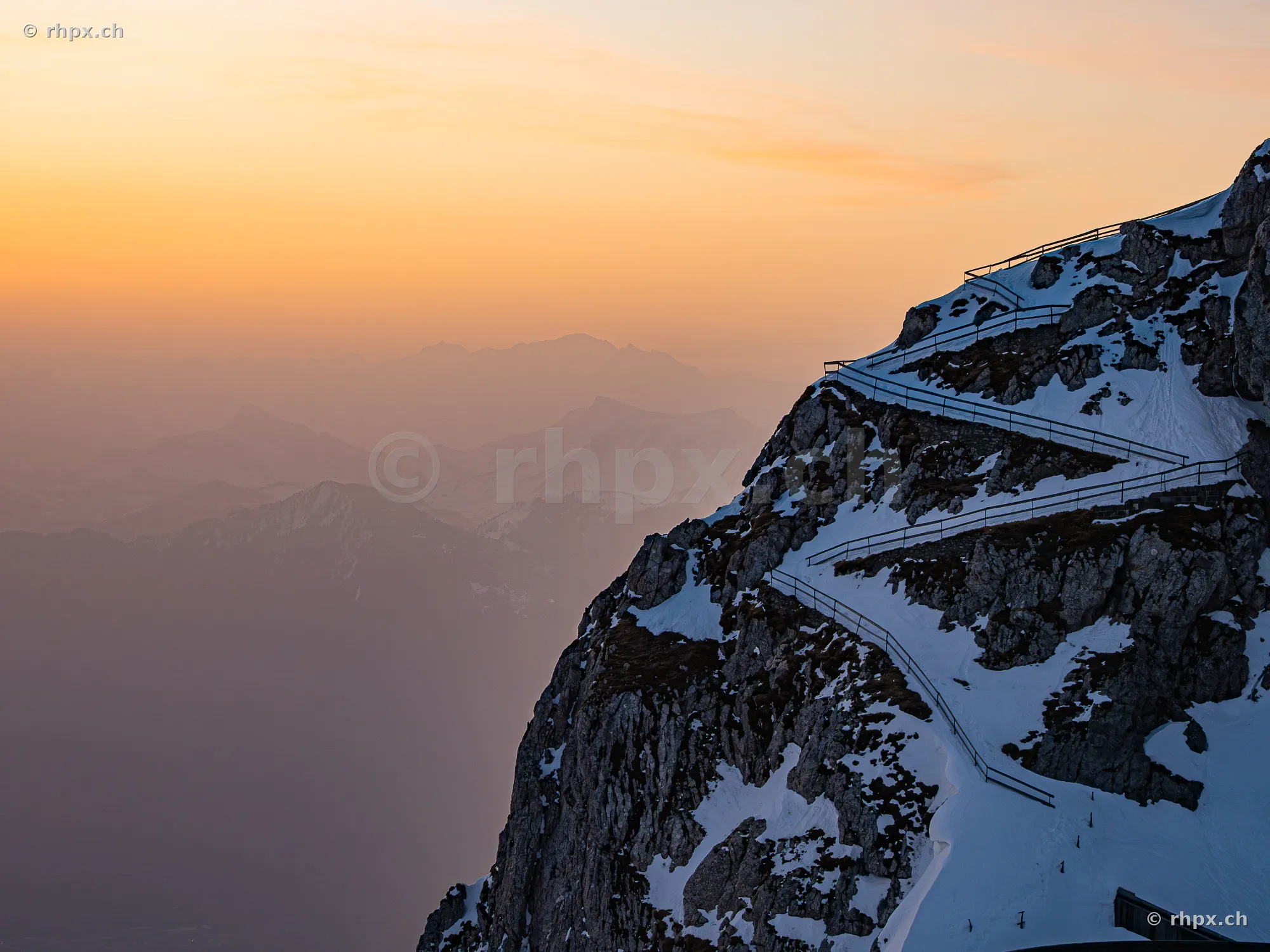 Snow-covered mountain trail on Mount Pilatus overlooking the Alps at dusk