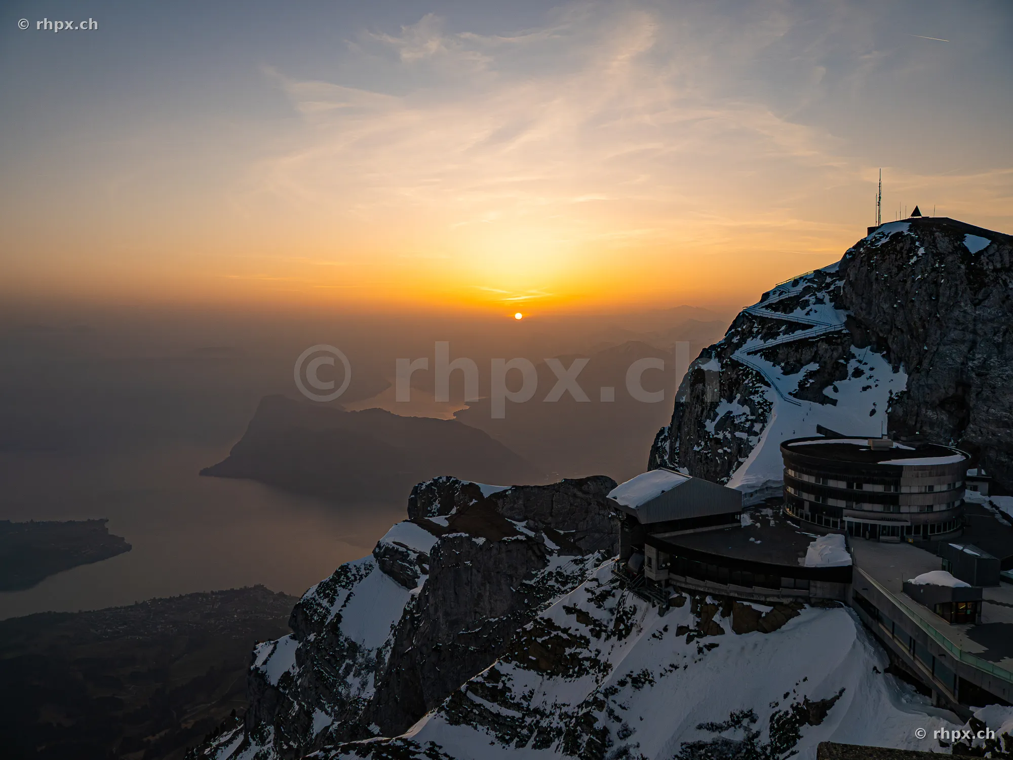 View of the Pilatus peak with Hotel Bellevue and snow-covered rocks in the warm light of the sunset