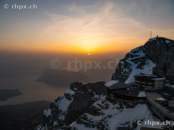 View of the Pilatus peak with Hotel Bellevue and snow-covered rocks in the warm light of the sunset