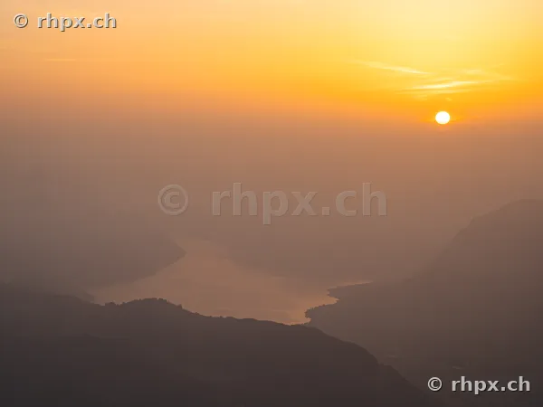View from Mount Pilatus over Lake Lucerne shrouded in haze during sunrise.