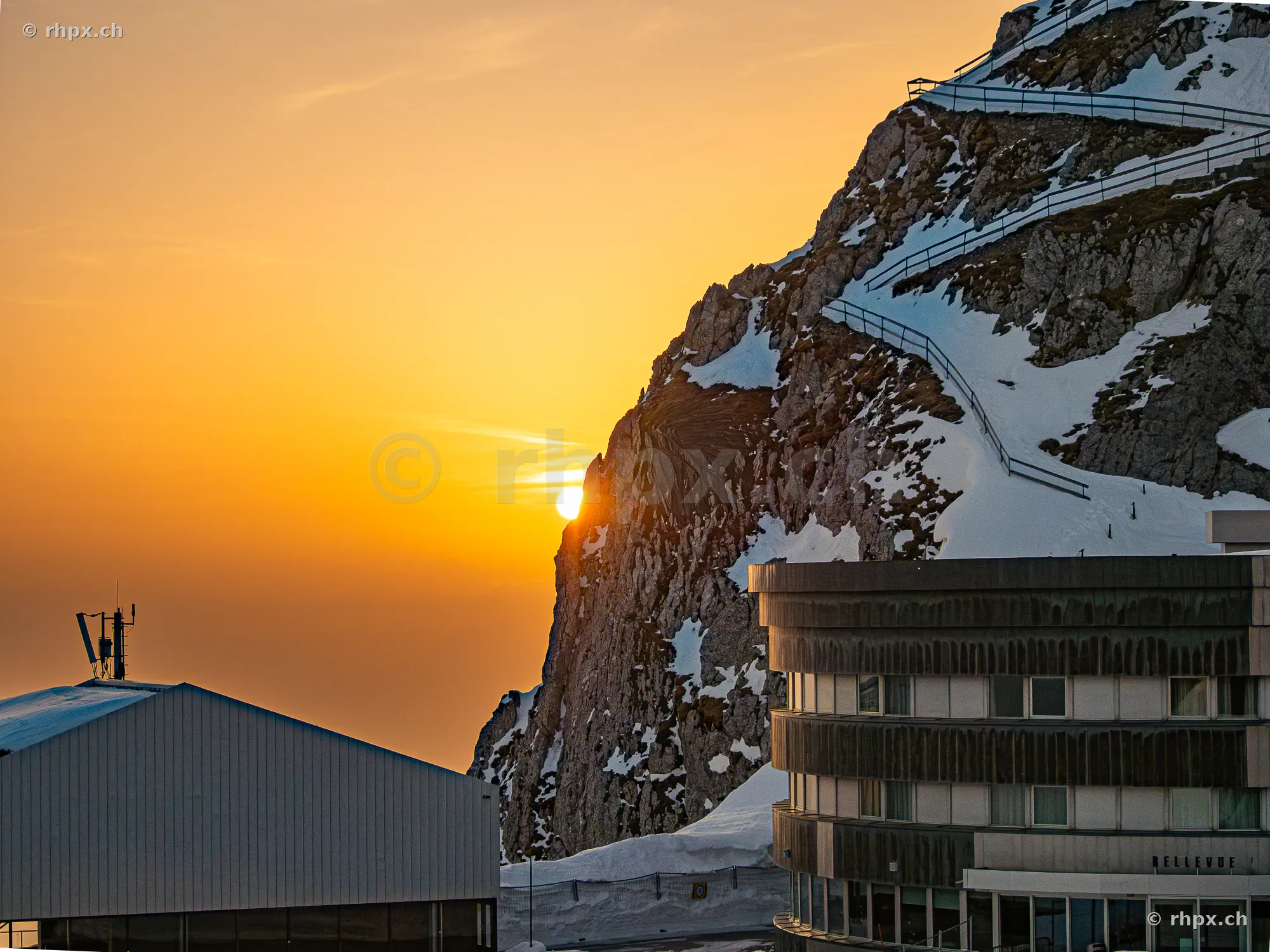 Sunset behind the rock face on Mount Pilatus with Hotel Bellevue in the foreground.
