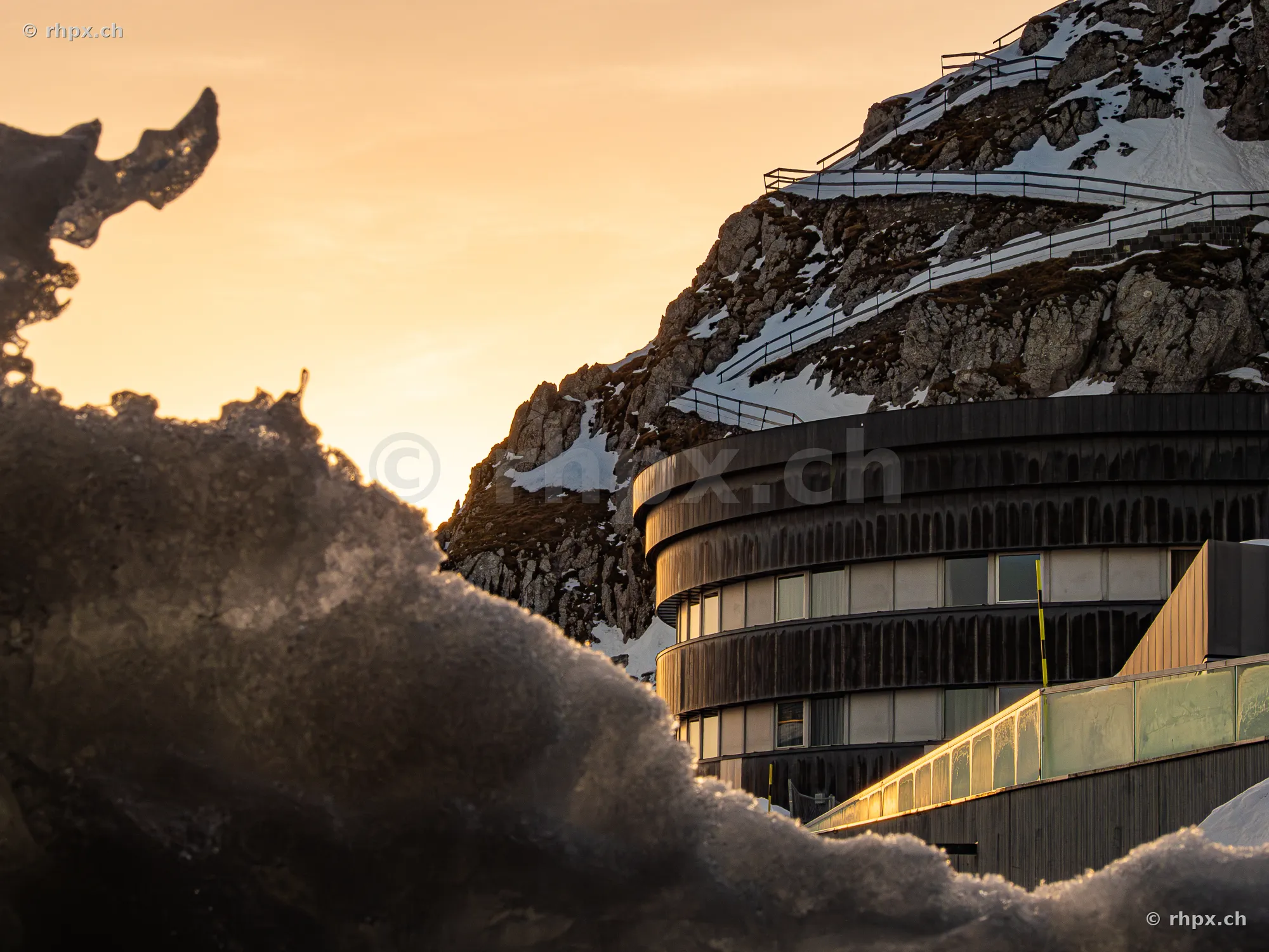 Hotel Pilatus-Kulm in golden evening light in front of snow-covered rock