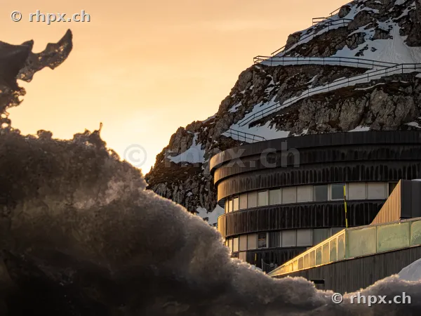 Hotel Pilatus-Kulm in golden evening light in front of snow-covered rock
