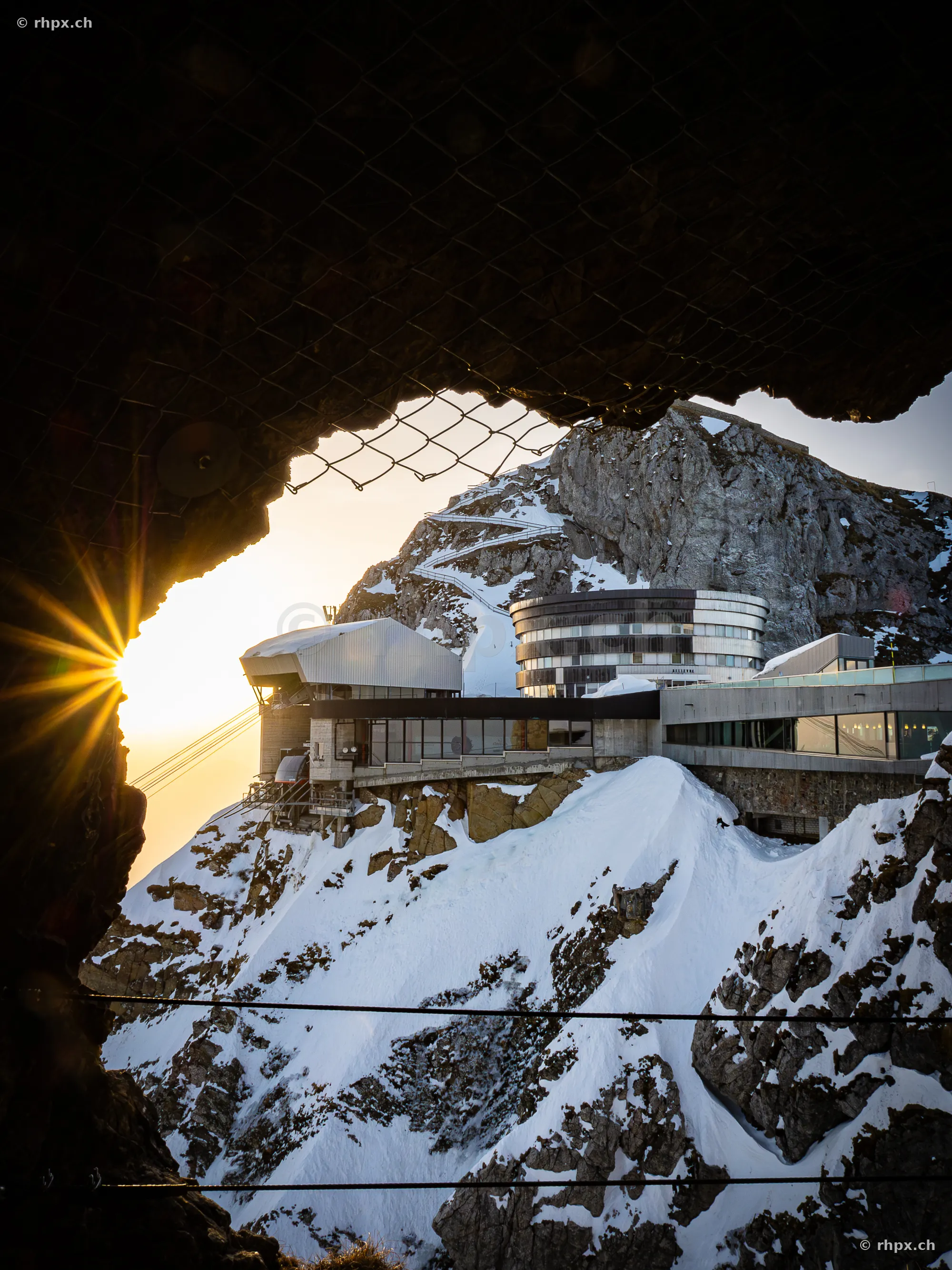 Blick aus einem Felstunnel auf die Hotelgebäude und Bergstation auf dem Pilatus im Winter