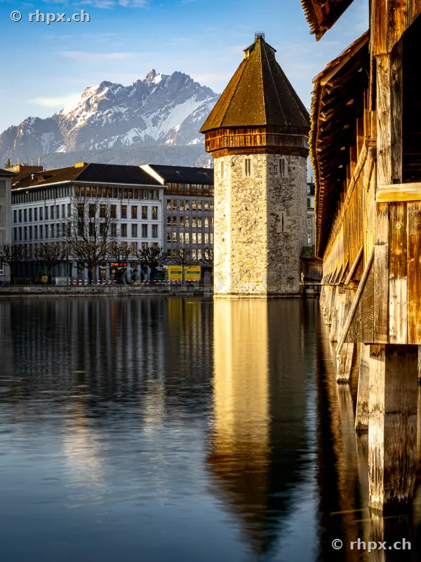 The historical Wasserturm of the Chapel Bridge in Lucerne with the snow-covered Mount Pilatus in the background.