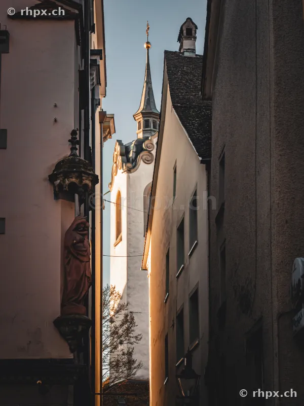 View through a narrow alley of the Jesuit Church tower in Lucerne during evening light