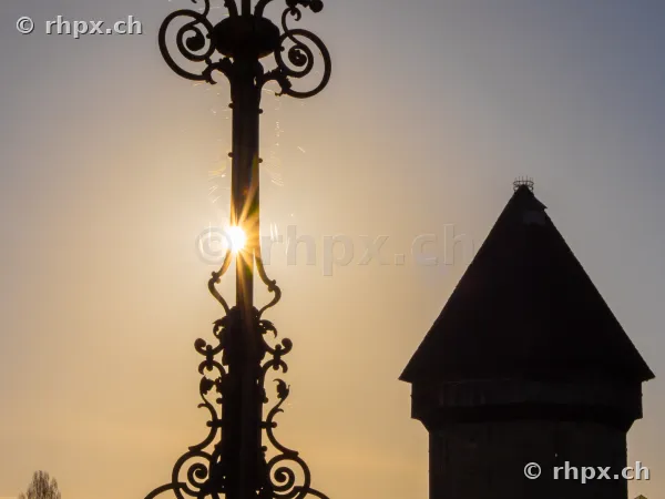 Silhouette of an ornate lantern and the Water Tower against the sunset in Lucerne