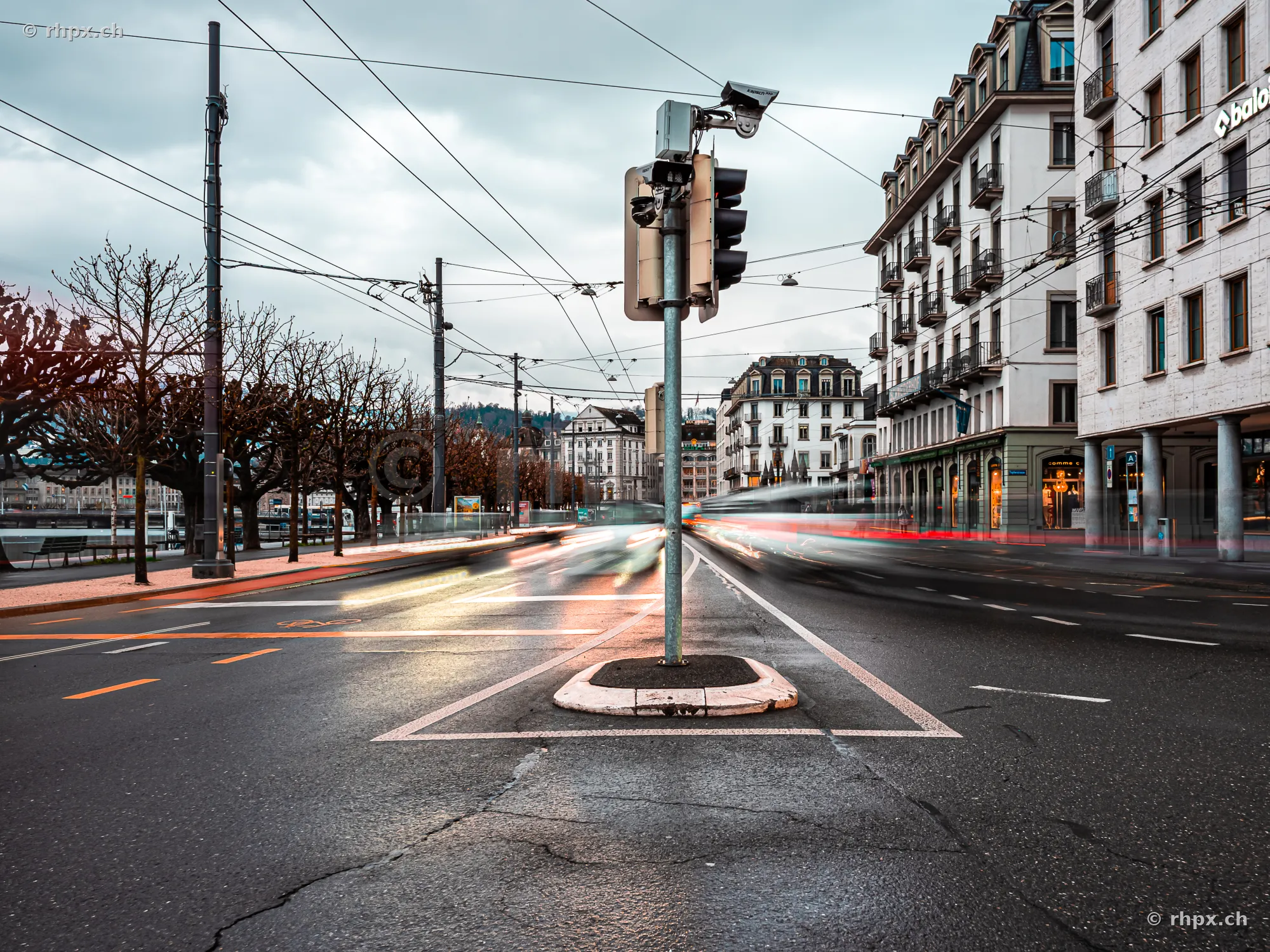 Lucerne Schweizerhofquai with traffic light and passing vehicles under a cloudy sky