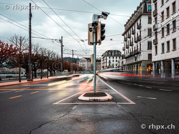 Luzern Schweizerhofquai mit Ampel und vorbeifahrenden Fahrzeugen bei bewölktem Himmel