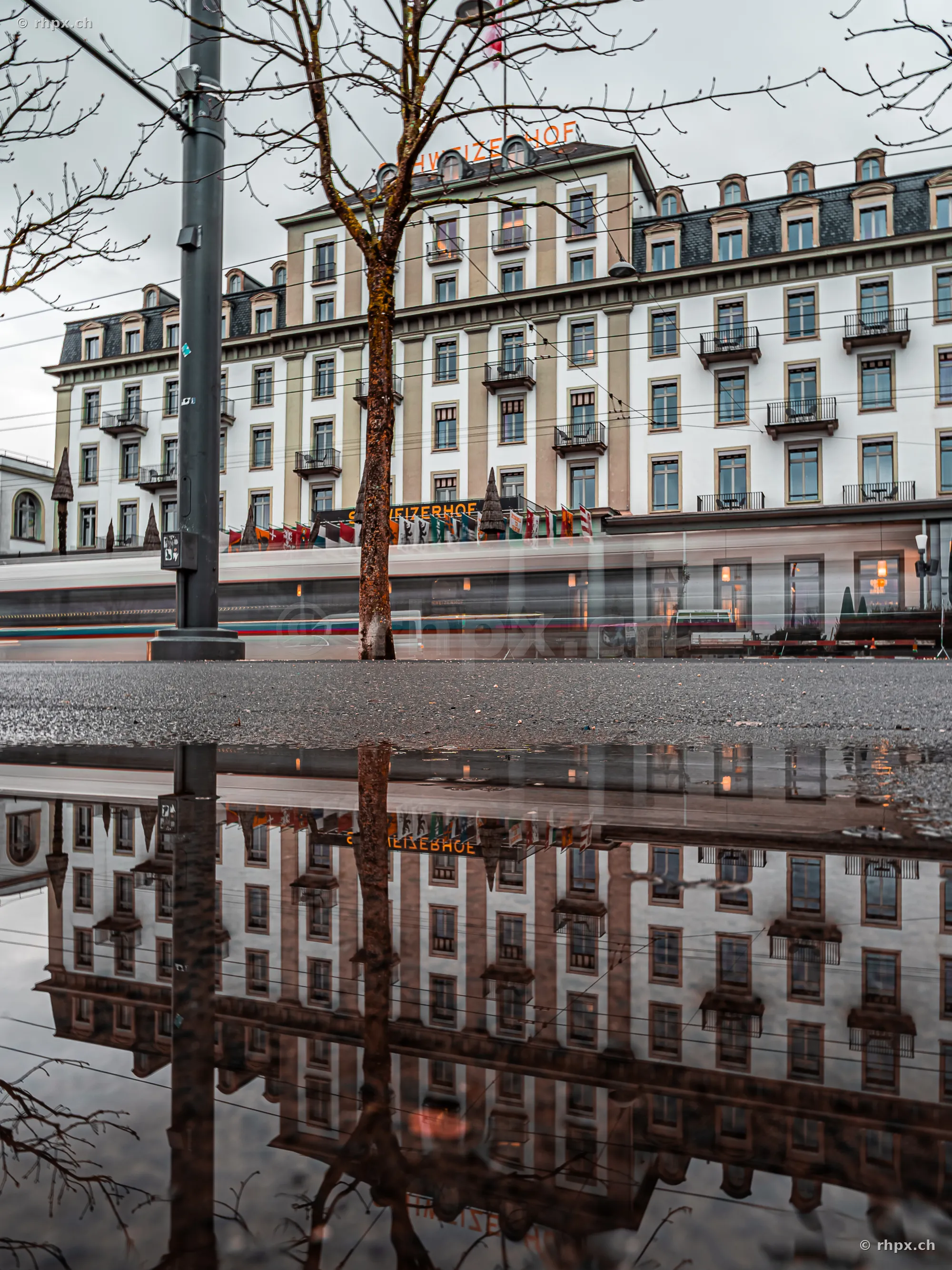Hotel Schweizerhof in Luzern gespiegelt in einer Pfütze am Boden