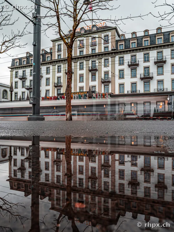Hotel Schweizerhof in Luzern gespiegelt in einer Pfütze am Boden