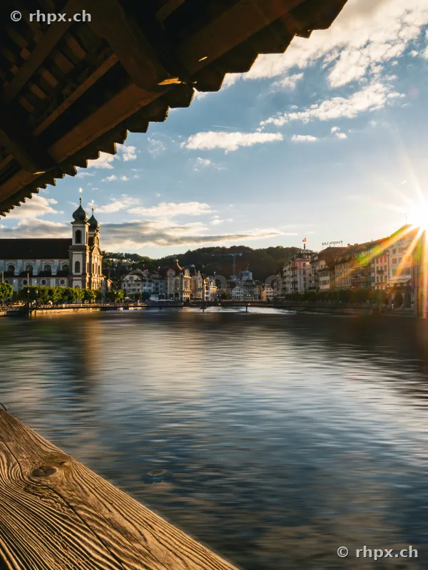 View from the Chapel Bridge towards the Jesuit Church and the Reuss river in Lucerne at sunset