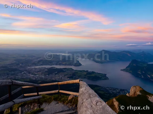 Wooden railing on Mount Pilatus overlooking Lake Lucerne and Central Switzerland at sunset.