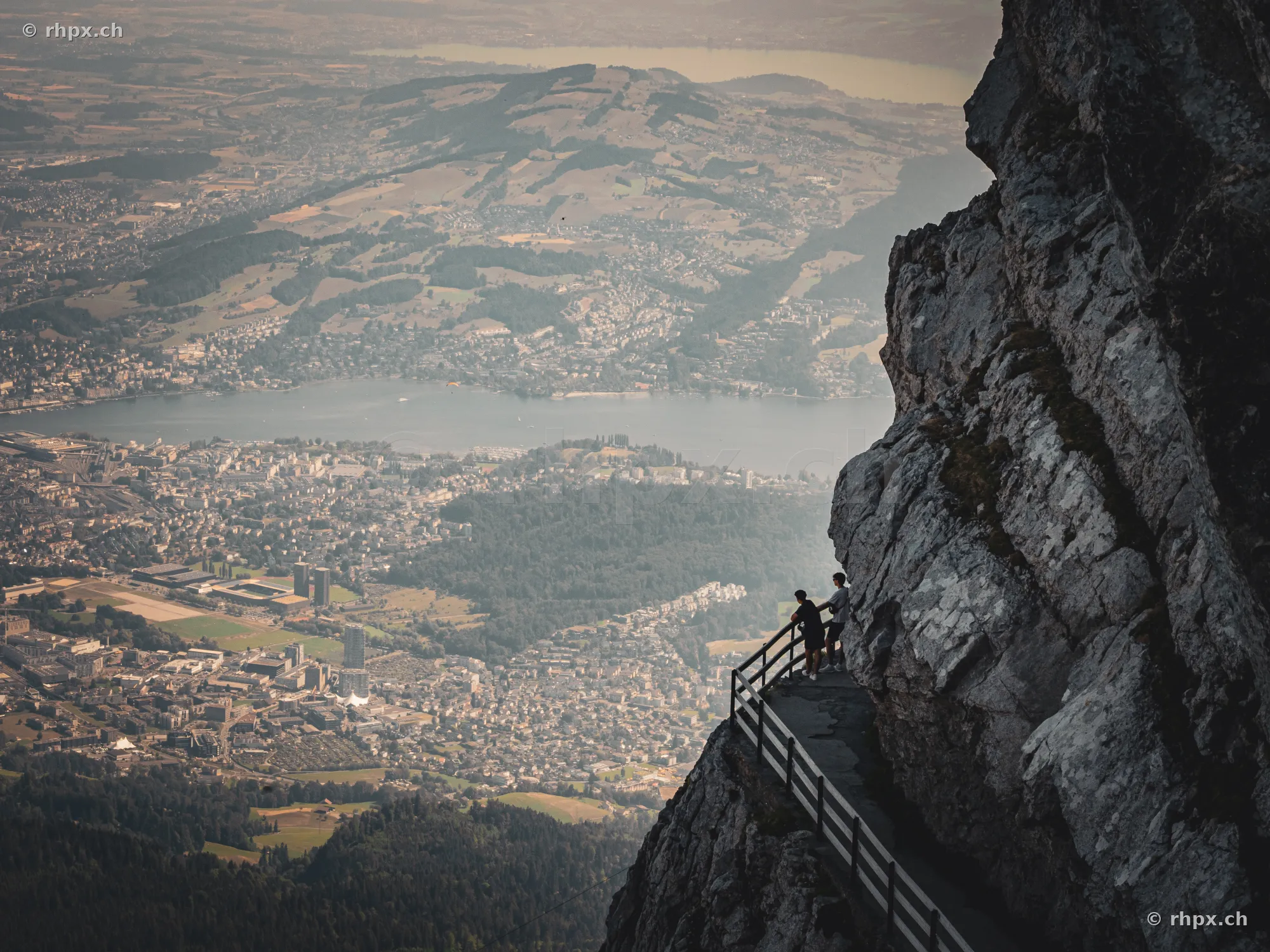 Personen auf dem Felsenweg am Pilatus mit Blick über den Vierwaldstättersee und die Stadt Luzern.