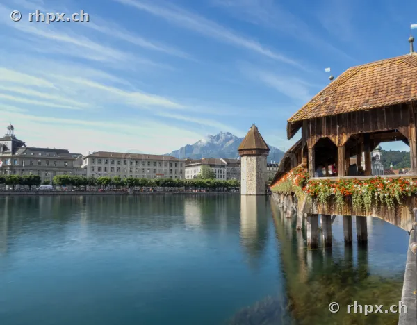 Chapel Bridge with flower-decorated roof over the Reuss, with Mount Pilatus in the background.