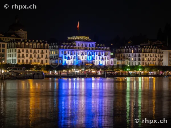 Beleuchtete Fassade des Hotels Schweizerhof Luzern am Ufer des Vierwaldstättersees bei Nacht