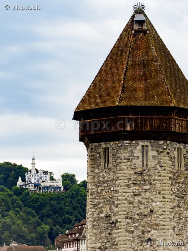 The historic Wasserturm in the foreground and the Château Gütsch hotel on the hill in the background in Lucerne.