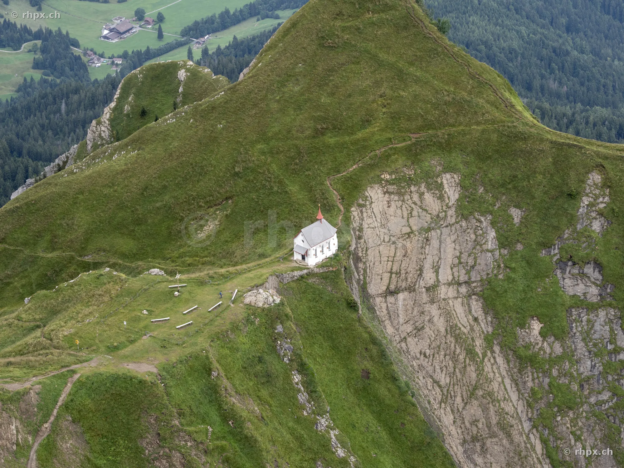 Luftaufnahme einer kleinen Kapelle auf einem grünen Gebirgsgrat nahe dem Pilatusmassiv
