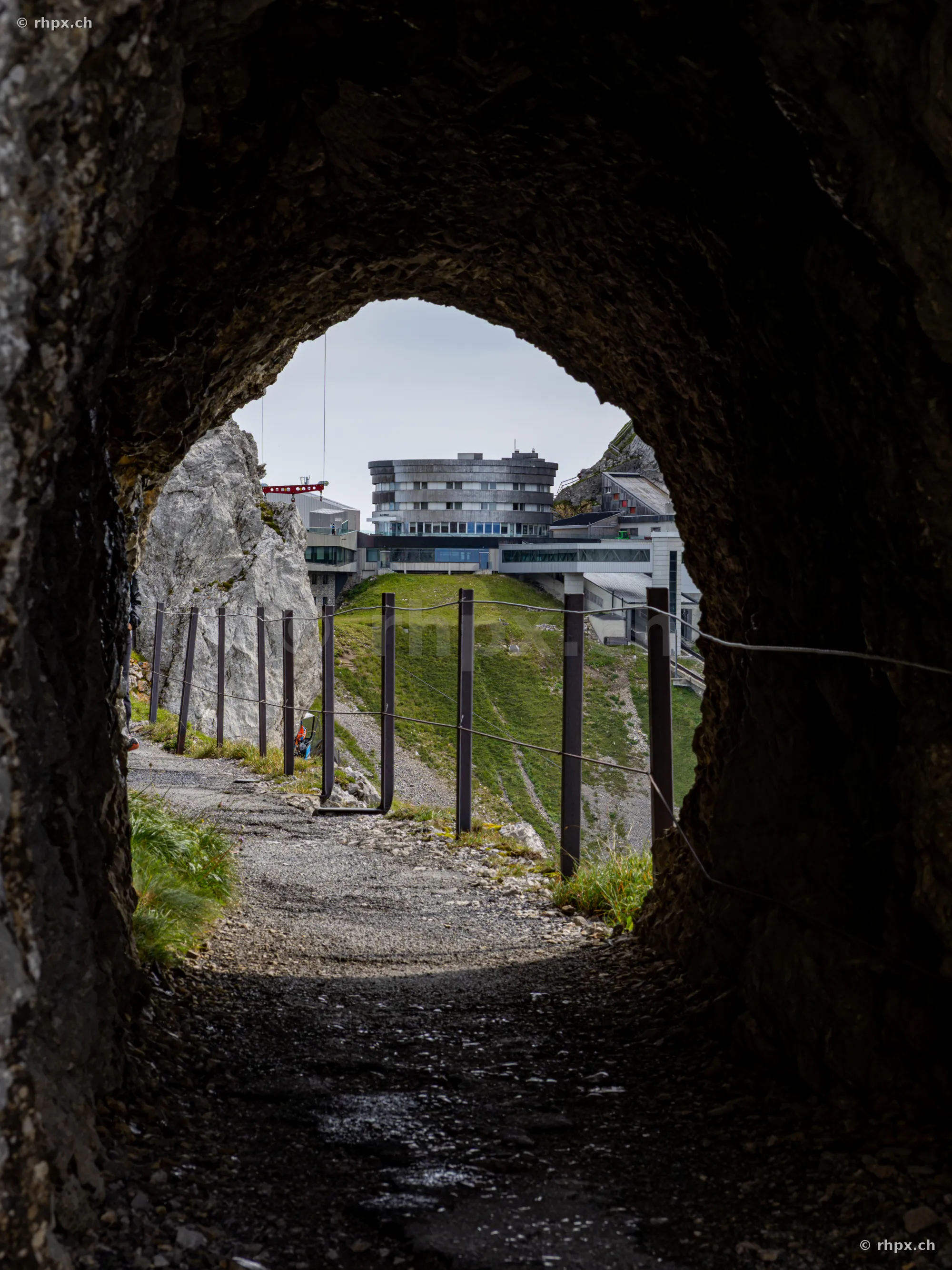 Blick aus einem dunklen Felstunnel auf das Hotel Bellevue am Pilatus Kulm.