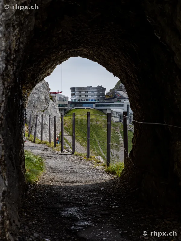 View from a dark rock tunnel towards Hotel Bellevue at Pilatus Kulm.