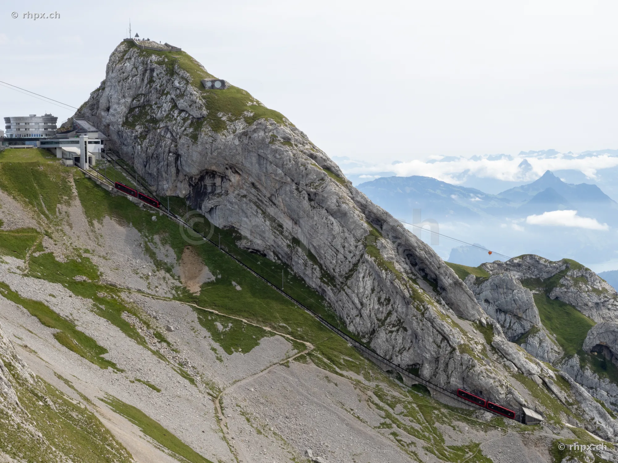 The red cogwheel train ascends the steep rock face at Pilatus Kulm.