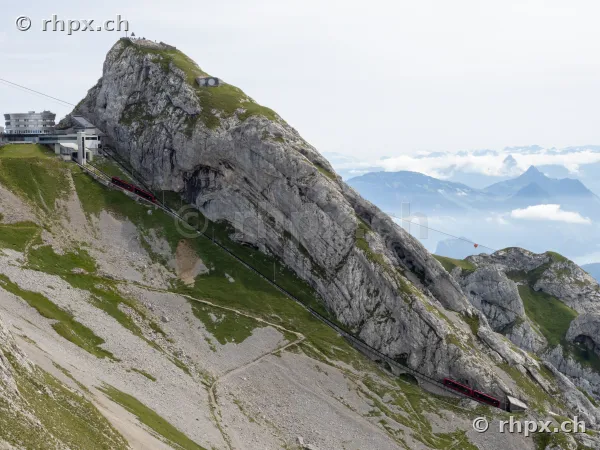 The red cogwheel train ascends the steep rock face at Pilatus Kulm.