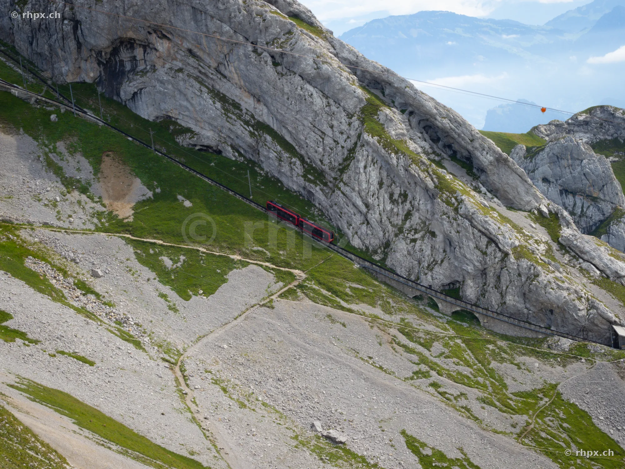 Red Pilatus cogwheel train traveling through rocks on Mount Pilatus