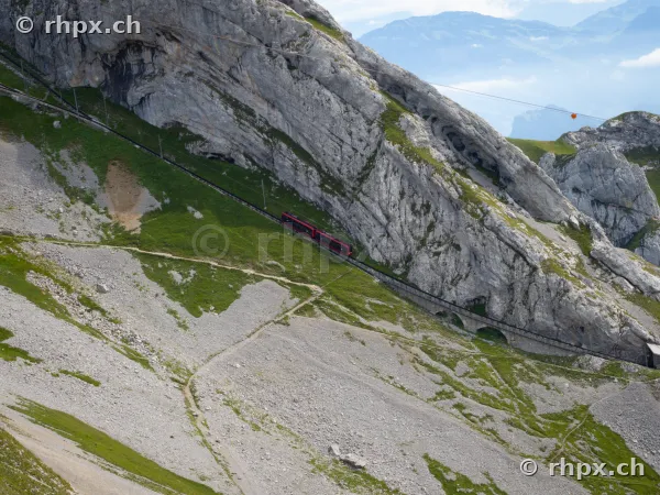 Red Pilatus cogwheel train traveling through rocks on Mount Pilatus