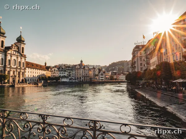 View of the Reuss river with the Jesuit Church and Old Town in Lucerne in backlit conditions.