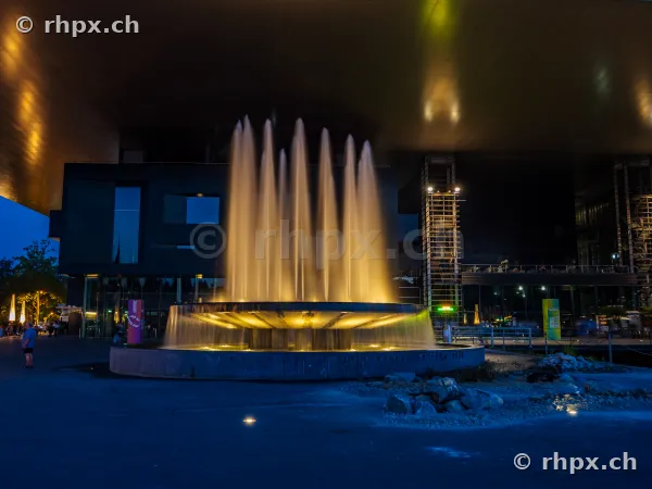 Illuminated fountain in front of KKL Lucerne at dusk
