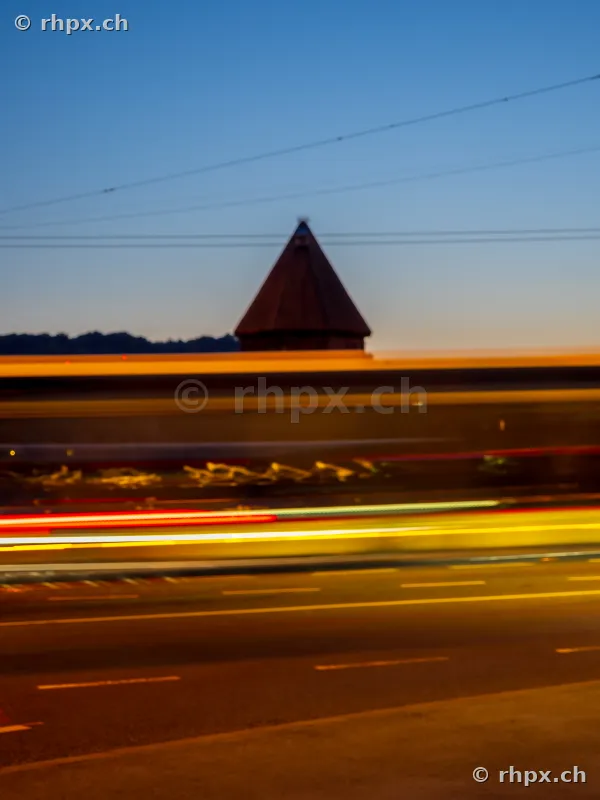 Water tower in Lucerne against a blue evening sky with long-exposure light trails from vehicles