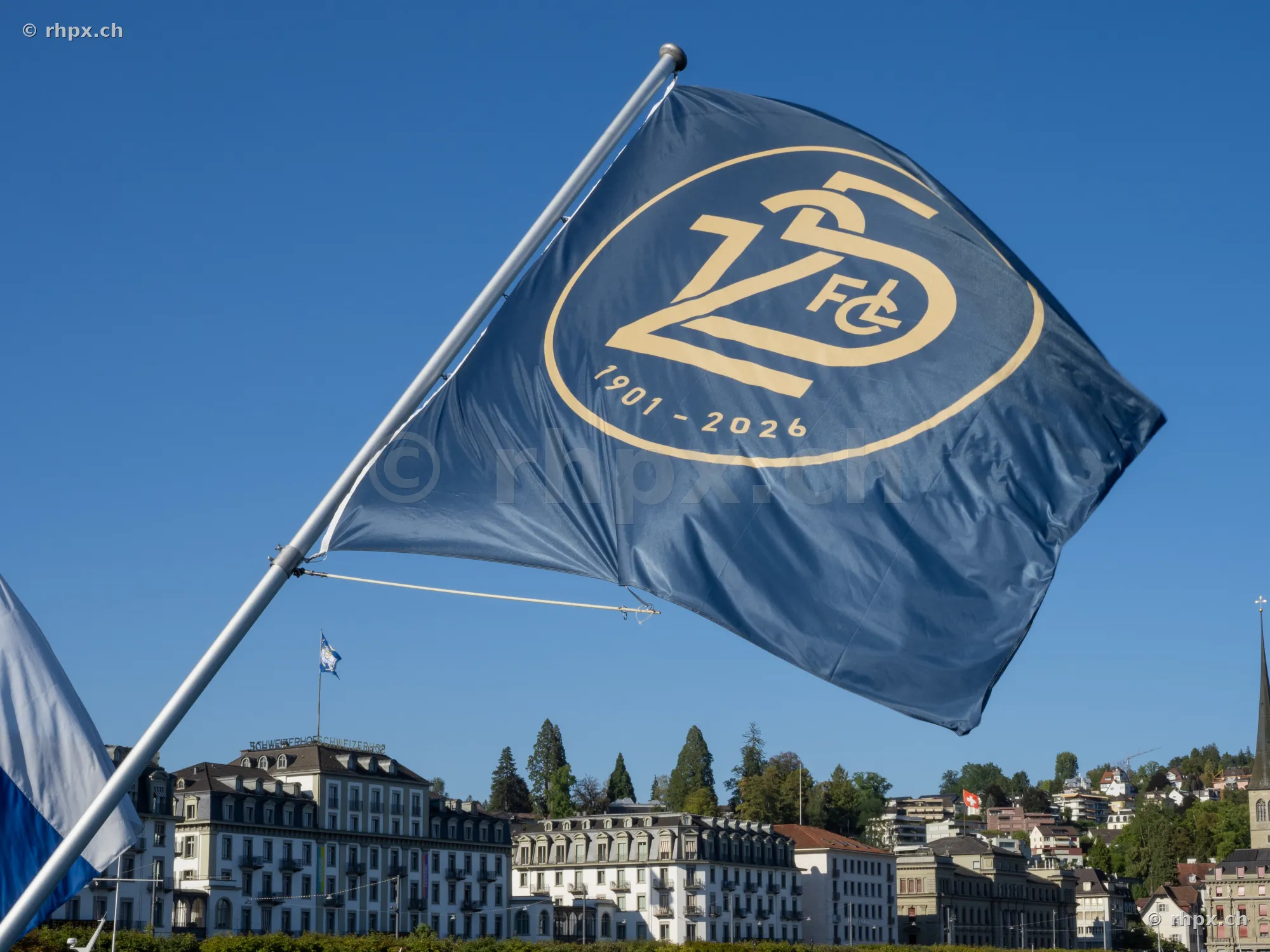 Blue FCL anniversary flag in front of the scenery of Lucerne