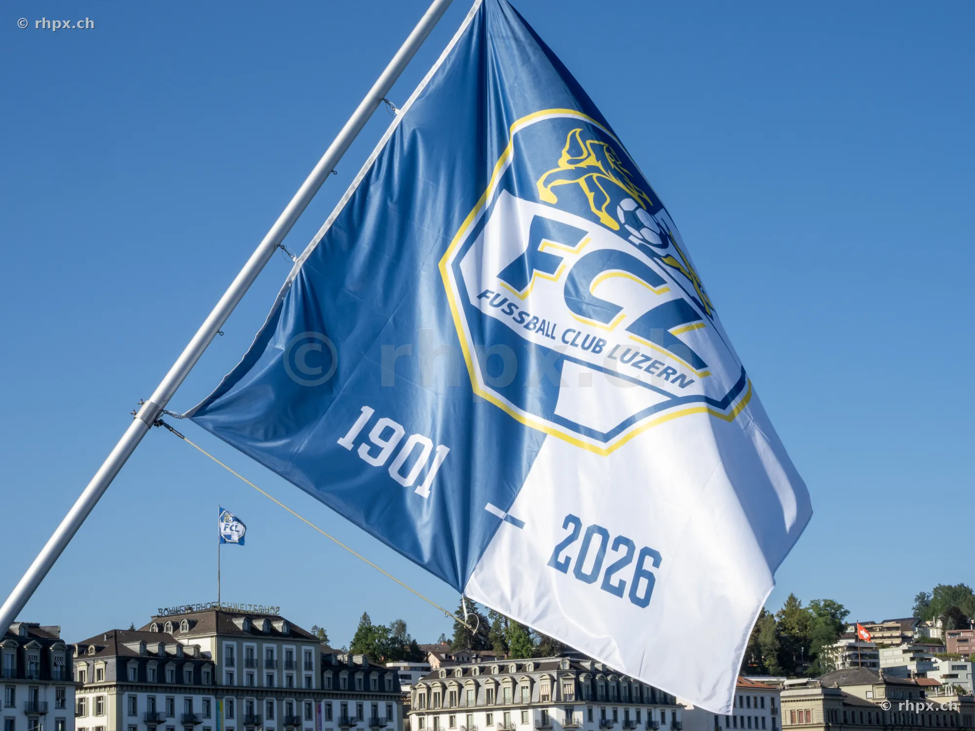 Blaue und weisse Fahne des FC Luzern mit Jubiläumsaufschrift vor blauem Himmel in Luzern