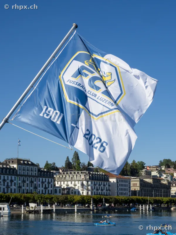 An anniversary flag of FC Luzern waving against the backdrop of the city of Lucerne at Lake Lucerne.