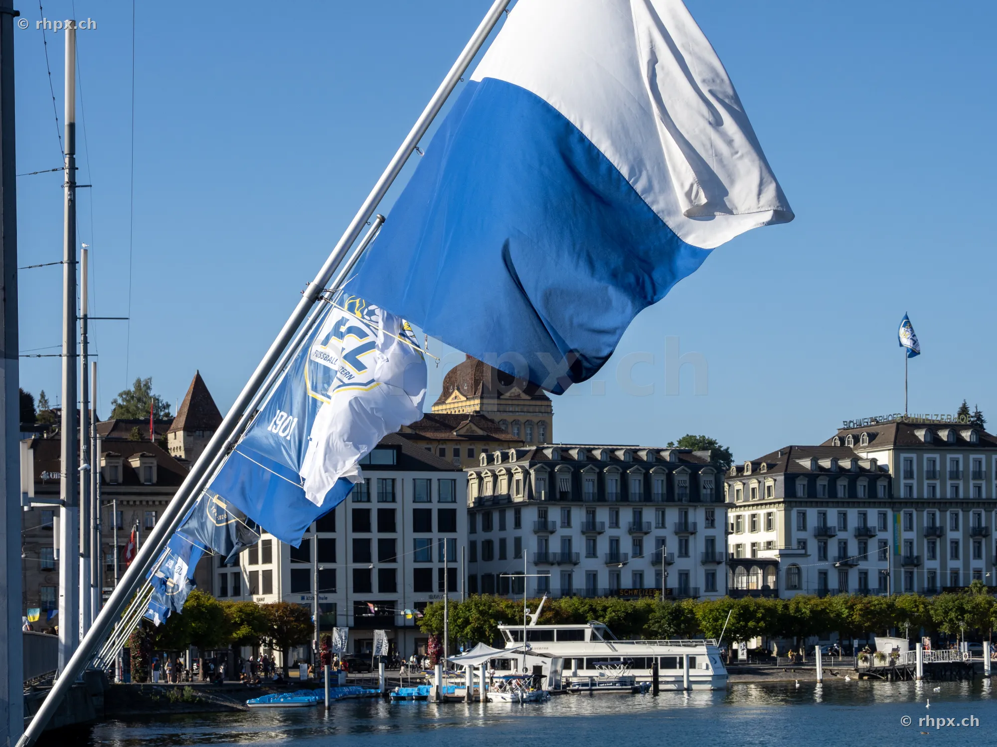 Blau-weisse Fahnen des FC Luzern wehen im Wind vor der Stadtkulisse von Luzern