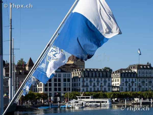 Blue and white FC Luzern flags blowing in the wind in front of the Lucerne cityscape