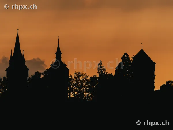 Silhouette of the Musegg towers in Lucerne against an orange evening sky
