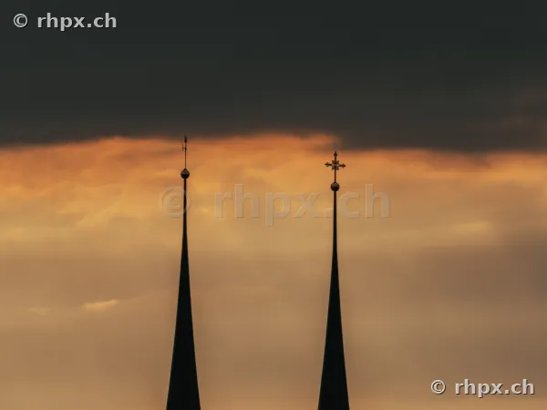 The two spires of the Hofkirche Lucerne against an orange evening sky