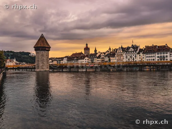 Wasserturm und die Kapellbrücke über die Reuss in Luzern vor einem wolkenverhangenen Abendhimmel