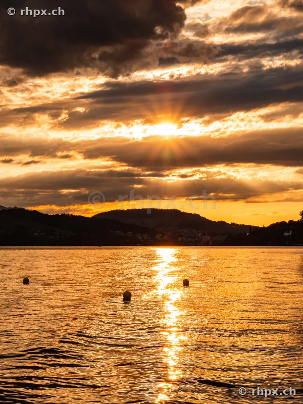 Golden sunset over Lake Lucerne with dark cloud formations