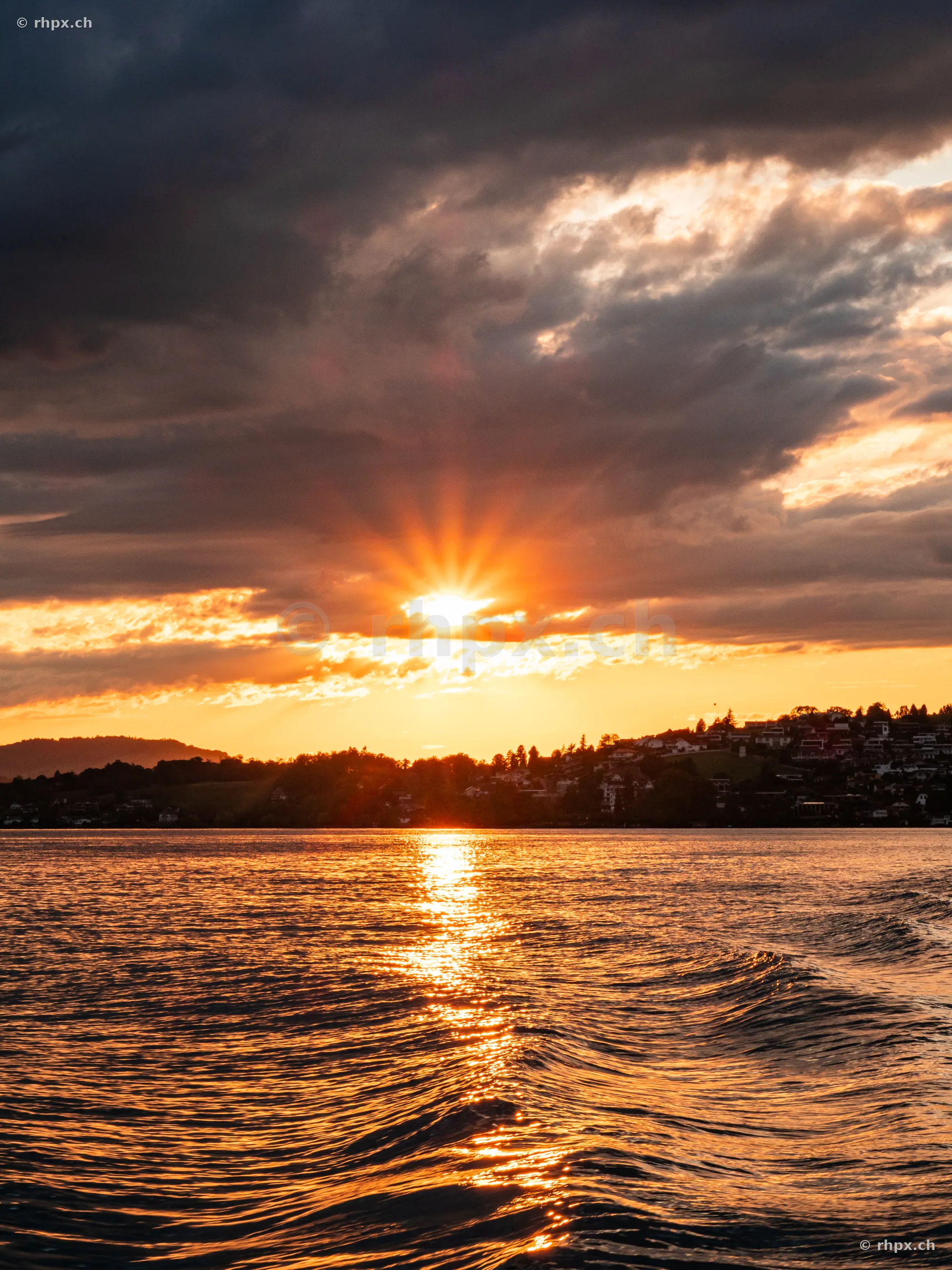 Lake Lucerne in the orange light of sunset with cloudy sky