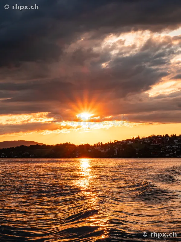 Lake Lucerne in the orange light of sunset with cloudy sky