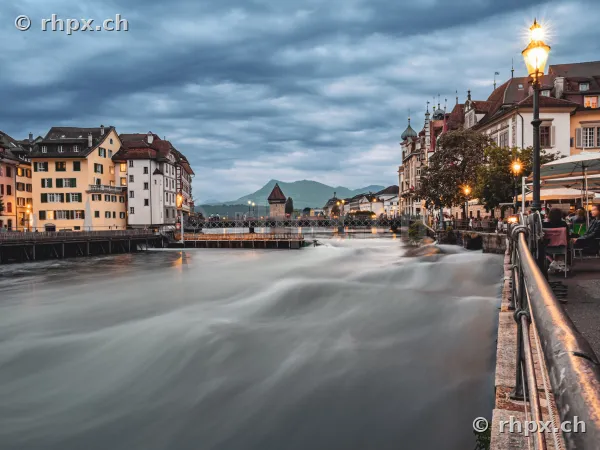 View of the Reuss river with the Chapel Bridge in the background in Lucerne under a cloudy evening sky