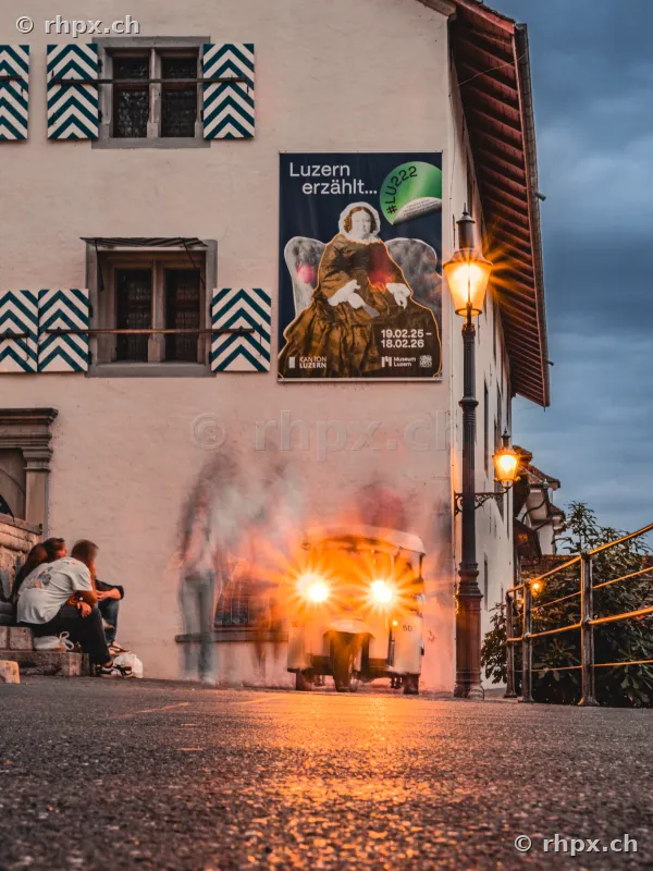 Facade of the Museum Luzern with a poster and a passing vehicle at dusk